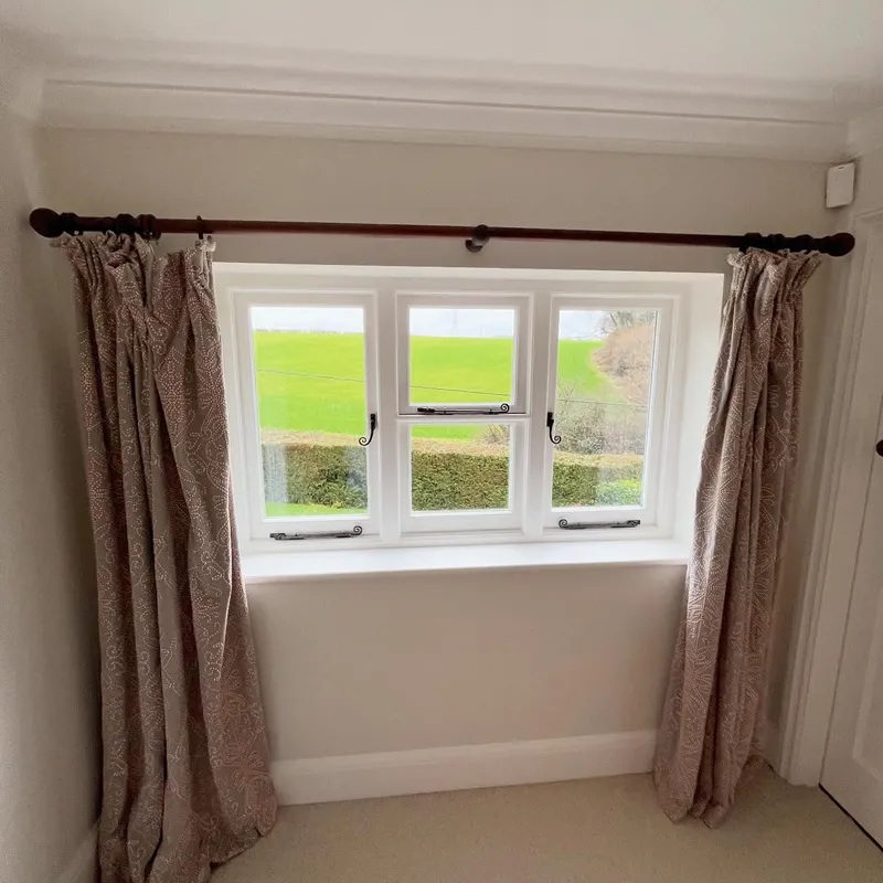 Bedroom window with blush-pink curtains and a white-painted frame