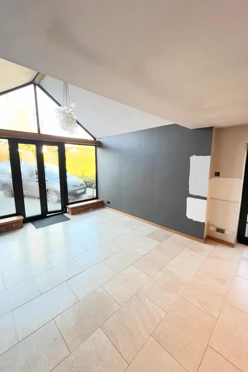 Open-plan room with a grey feature wall and black-framed apex glazing