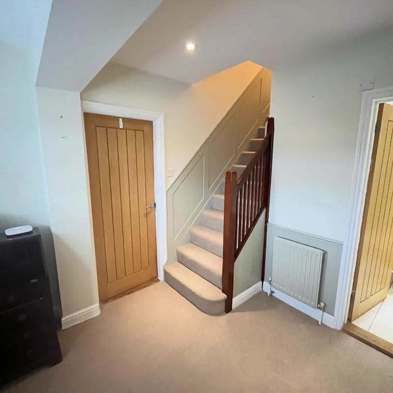 Hallway with an oak door and staircase against neutral walls