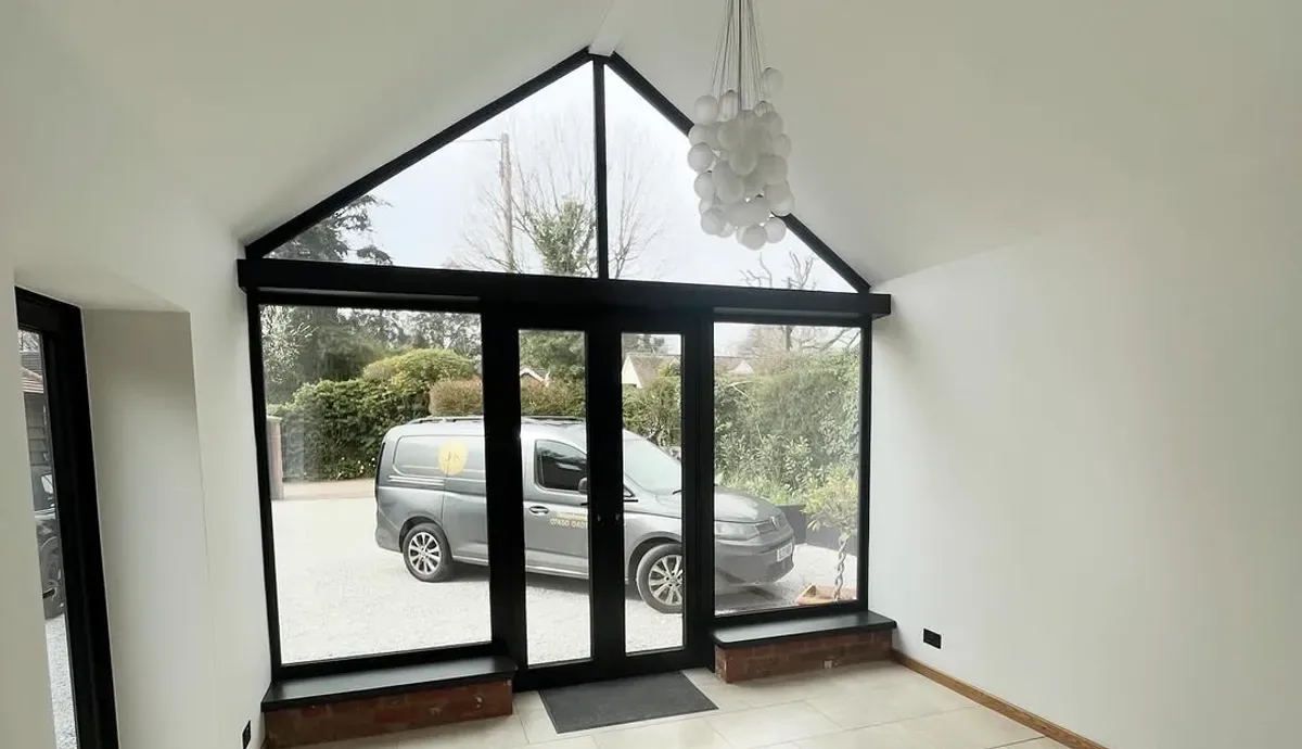 Finished vaulted living space with a black-framed apex window and white walls