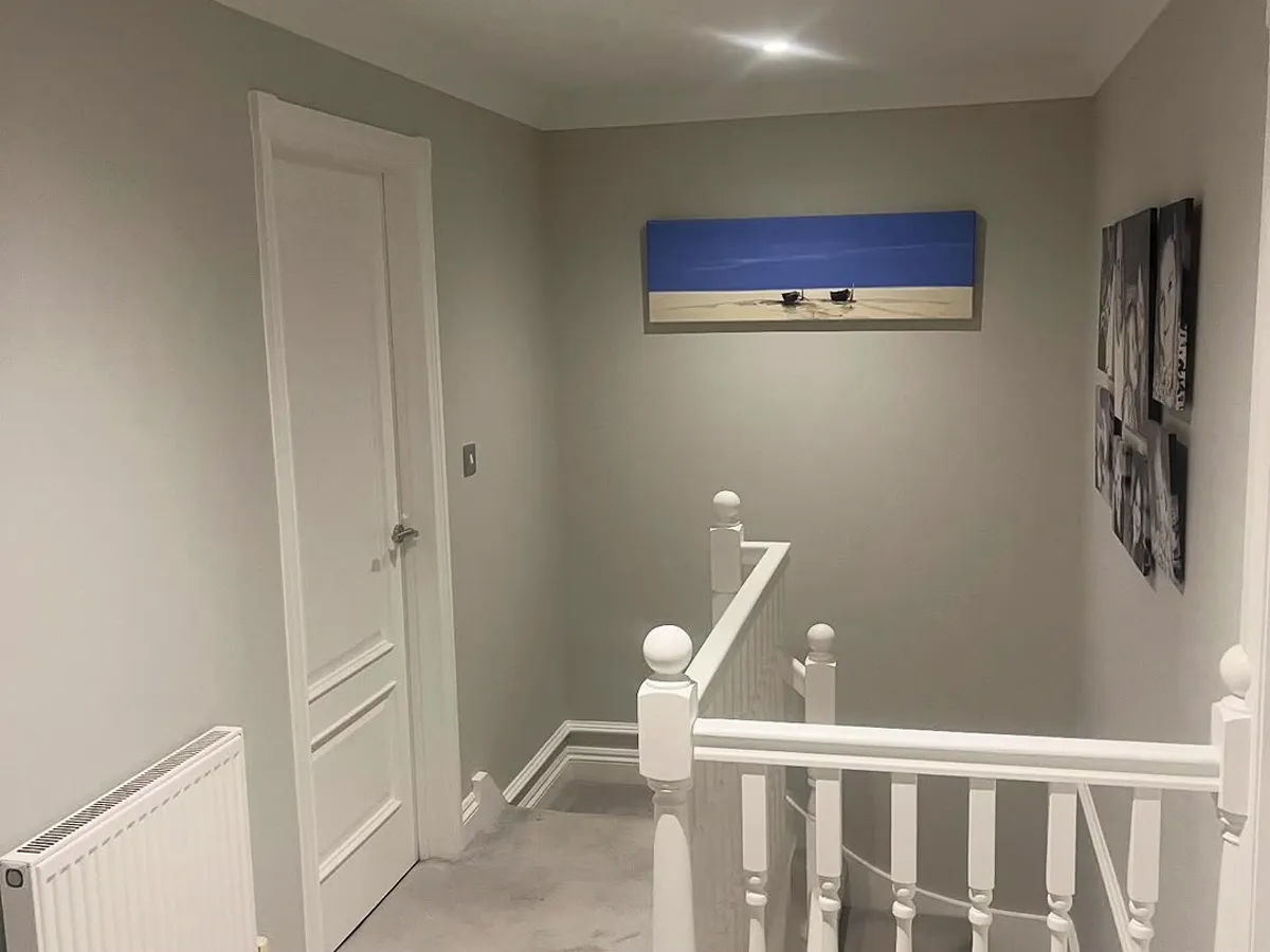 Finished landing with grey walls, a white-painted banister and downlights