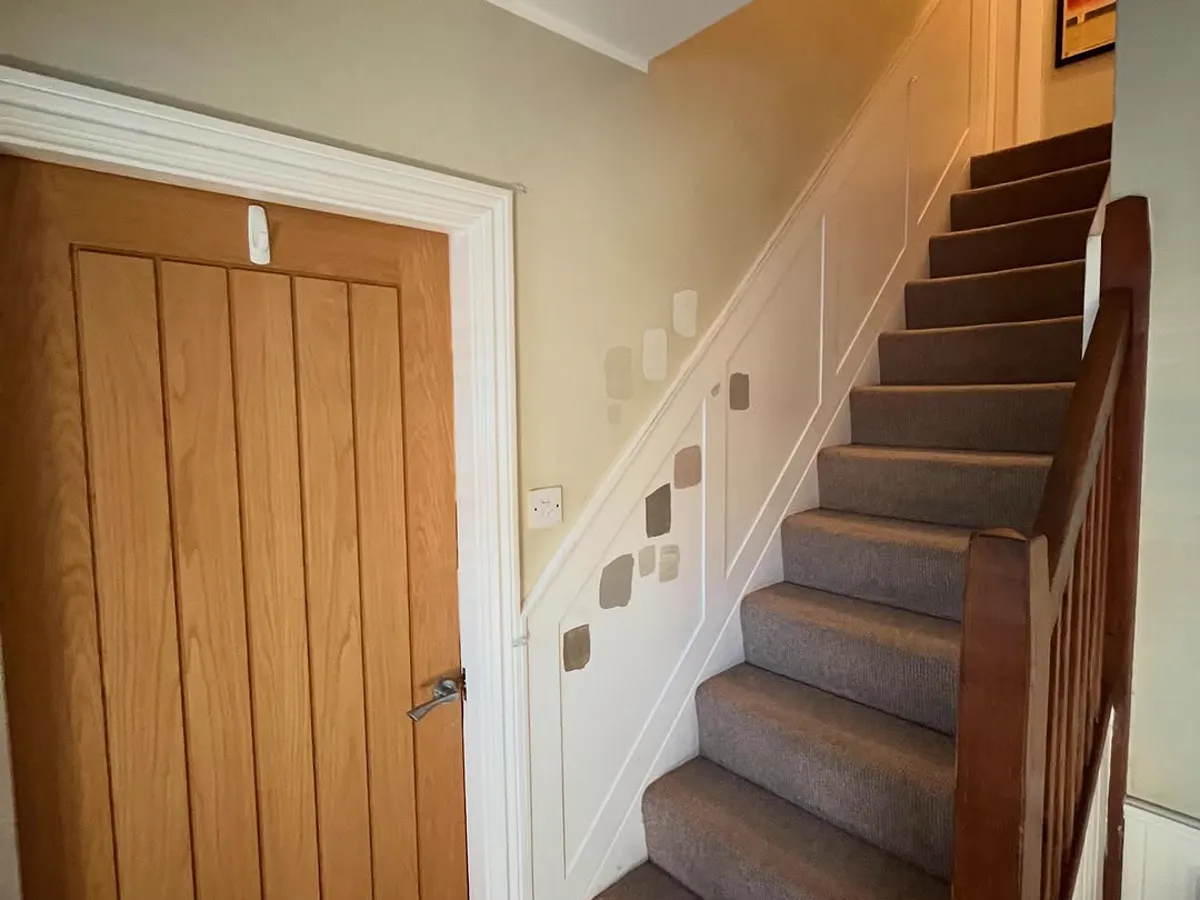 Finished hallway and staircase with an oak door and white panelled dado
