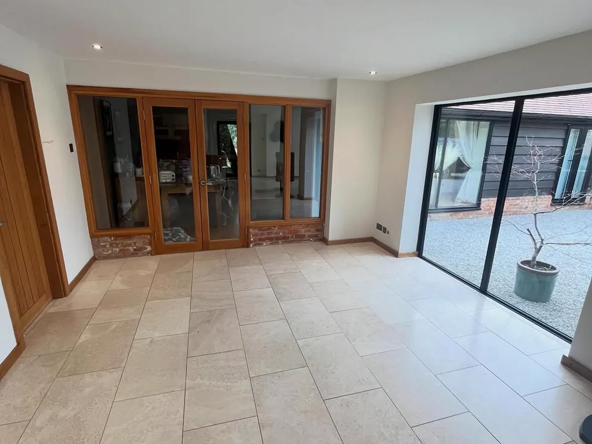 Finished open-plan living and kitchen space with white walls and large sliding doors